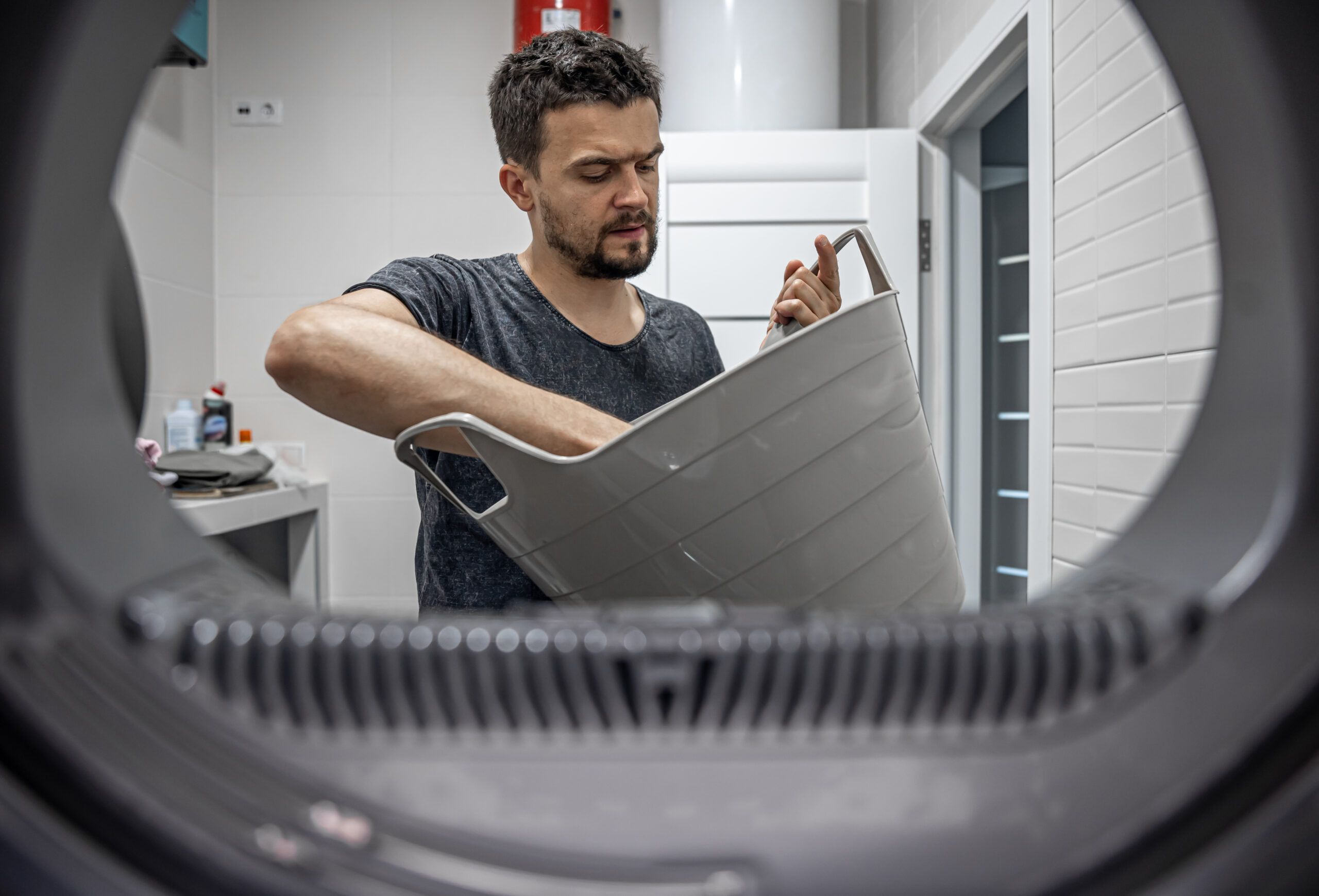 portrait-man-view-from-washing-machine-loading-washing-dirty-linen