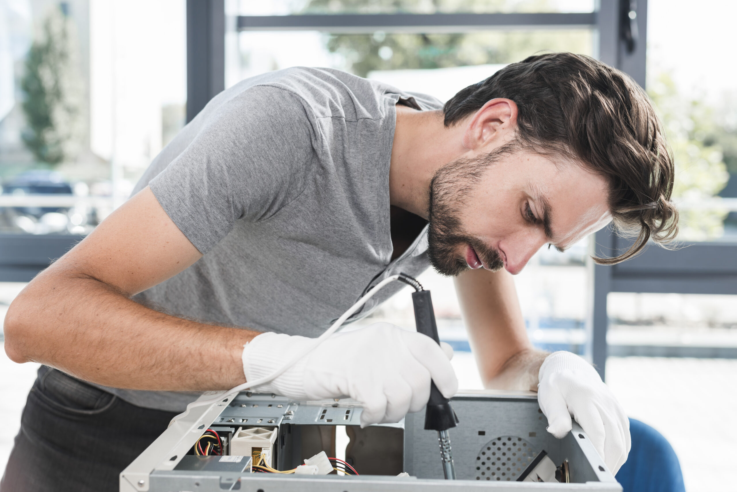 side-view-young-male-technician-working-broken-computer